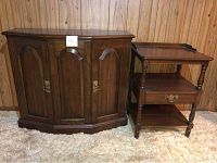 Closed wooden cabinet and open shelf unit positioned side by side against wood panel wall on carpet.