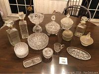 All clear glassware arranged on wooden table showing full set of decanters, bowls and covered dishes