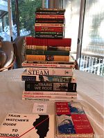 Photo showing a stack of about 20 railroad and train books, titles visible for various train and railroad guides, historical handbooks and spotter's guides.