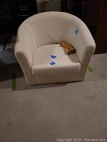 Front view of white Ikea Ektorp barrel chair with removable legs displayed on seat, showing cat claw damage and wear.