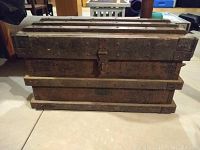 Front view of the antique heavy-grade wood and metal tool chest with metal reinforcements and patina.