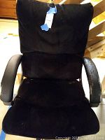 Front view of the black plush office chair showing cushioned seat and backrest and the worn armrests.