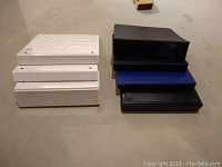 Top view of the six binders stacked in two piles, showing three white binders on left and two black and one blue on right.