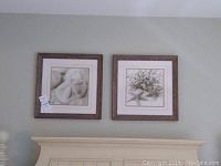 Two framed beach scene art prints hanging on a wall above furniture, showing both prints together.