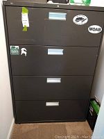 Front view of the 4-drawer metal lateral file cabinet showing the closed drawers with stickers visible on the front.
