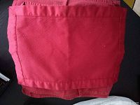 Photo of single red cloth napkin showing fabric texture and hemmed edge.