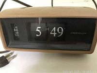 Front view of vintage brown Westclox electric flip number clock showing time 5:49 and analog alarm dial.