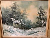 Framed oil painting of a rustic cabin in a snowy winter landscape with trees and cloudy sky.