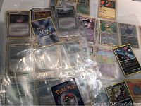 Photo showing several Pokemon cards in plastic sleeves with a visible 2004 World Series card and assorted Trainer and Pokemon cards.
