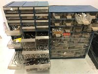 Two blue metal cases each with multiple clear plastic drawers containing various metal fasteners, nuts, bolts, screws, washers, and hair pins