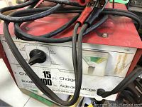 Front panel and cables of Photomaster battery charger showing rotary switch and analog charge meter.