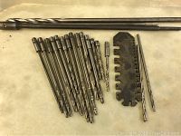 Overview of set showing multiple drill bits and sizing gauge tool laid out on surface