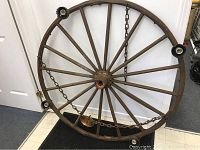 Full view of the large wagon wheel lamp frame showing wooden spokes, metal rim, and hanging chains.