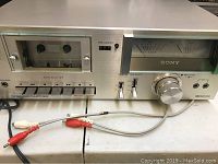 Front view of the Sony tape deck showing cassette compartment, control buttons, knobs, and RCA cable connectors.