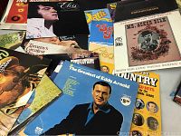 Photo showing several vinyl records laid out including Elvis Presley, Bobby Vinton, Eddy Arnold, and others, highlighting variety of artists and genres.