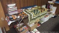 Overall view of two quilt tops on table, boxes of fabric scraps and magazines