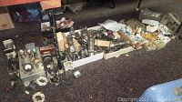 Wide view showing multiple vacuum tubes, parts, electronic devices on floor with carpet
