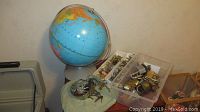 Globe placed next to a plastic container with various vintage locks and keys scattered around and inside it.