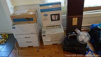 Ricoh Aficio AP610N three paper tray printer, additional Ricoh printer, various electronics including DVD/CD player, VHS players, speakers, and digital picture frame in boxes.