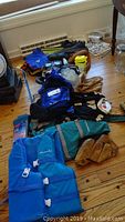 Photo showing the full assortment of sports and snorkeling gear including gloves, life jackets, bags, and fins laid out on wooden floor