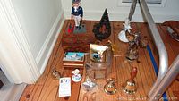 Full lot of items including Uncle Sam bank, carved wooden music box, Reuge music box with brass bells, and various small figurines and bells