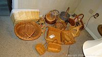 Photo showing assortment of woven baskets including three Longaberger baskets plus various other baskets and collectible tins on carpeted floor.