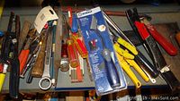 Various hand tools including hammers, screwdrivers, pliers, utility knives, and Kobalt-brand tools arranged on a shelf.