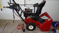 Full view of red Toro snow blower showing front auger housing, wheels, handles, and discharge chute
