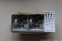 Top view of a stack of 38 antique stereo cards, showing black and white image of a man on horseback and children