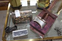 Overview photo of lot contents including stereo viewer on wooden box, antique shoe, eyeglasses, floral stereo card holder tube, and a black and white panoramic stereo card.