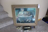 Framed oil painting leaning against wall next to stairs with new brass gallery light and hardware laid out in front.