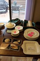 Wide shot of set laid on table showing plates, bowls, serving pieces with some labelled with pink stickers