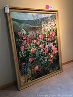 Full view of framed acrylic floral landscape leaning against wall