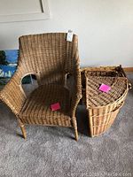 Wicker chair with armrests and backrest alongside a large lidded wicker basket. Both items feature natural brown wicker construction.