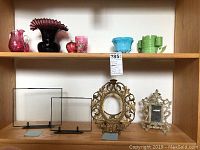 Full shelf view showing all glass vases and cups on top shelf and picture frames below.