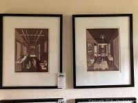 Two framed etchings hanging side by side on a wall, showing an interior with dogs, each in black frames with white mats.