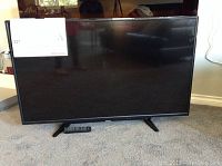 Front view of Toshiba TV on stand with remote placed in front