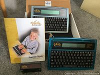 Two Writer Learning System keyboard instructor devices shown together with instruction manuals and keyboard covers inside a cardboard box.