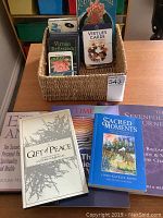 Photo of basket with several Oracle Card decks including Wisdom, Virtues, and Virtues Reflection cards and multiple books such as A Gift of Peace and The Seven Fold Journey.