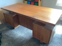 Front view of entire teak desk showing top, pedestals and base