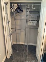 Overview of adjustable closet organizer frame with hanging rods and some hangers inside a closet space