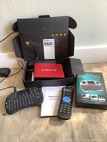 Sidekick TV device, mini wireless keyboard, remote control, power cord, user manual, and box all displayed on floor.