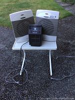 Two white Sunbeam electric heaters and one smaller black heater on a white table outside on a gravel surface.