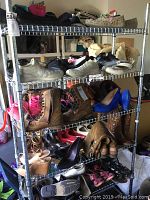 Metal shelving unit with approx. 35 pairs of mixed boots and shoes of various styles and brands.