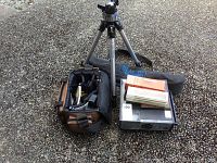 Lot setup showing Mainfrotto tripod, camera case with lens and accessories, and GAF 2690 slide projector with slide boxes.