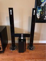 Front view of the LG digital flat speaker system showing two tall speakers, black subwoofer, and horizontal speaker