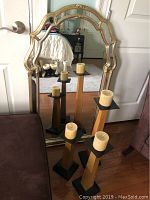 Full view of mirror leaning against door with three candle pedestals positioned in front, showing size and design details