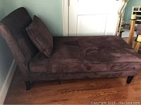 Side view showing the full length and height, cushion on seat, dark wooden legs.