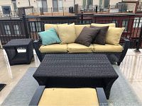 Front view of sofa with cushions, coffee table and side table on balcony