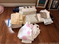 Assortment of folded bath towels including light yellow patterned towels stacked together, white bathrobe with pink polka dots in front, boxed grab bars visible at the back.